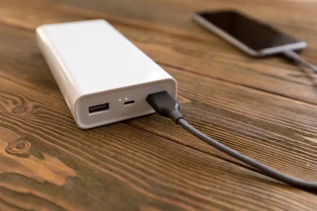 Powerbank i smartfon leżące na drewnianym stole