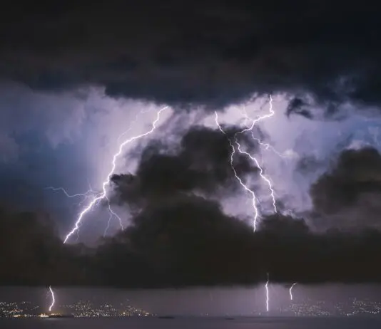 Pioruny uderzające za ciemnymi chmurami burzowymi nad panoramą miasta