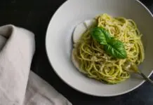 Talerz spaghetti z zielonym sosem pesto i listkami bazylii
