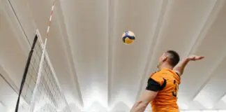 Siatkarz atakujący piłkę nad siatką podczas meczu w hali