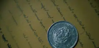 Zabytkowa srebrna moneta leżąca na starym, ręcznie zapisanym dokumencie