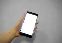 Dłoń trzymająca smartfon z pustym ekranem