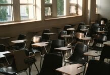 Pusta sala lekcyjna z rzędami ławek i światłem wpadającym przez okna
