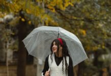 Osoba z parasolem idąca ulicą w strugach jesiennego deszczu