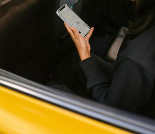240 tysięcy kierowców Ubera mówi „dość”. Gigantyczny pozew także z udziałem Polaków Osoba w samochodzie trzymająca smartfon z aplikacją przewozową
