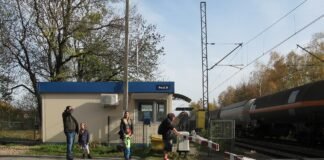 Rogatki zamknęły się, a auto stoi na torach. Ekspert PLK: o życiu decyduje 11 sekund Przejazd kolejowy z opuszczonymi rogatkami, w tle przejeżdżający pociąg towarowy