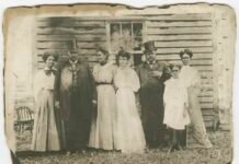 Czarno-białe archiwalne zdjęcie rodziny pozującej przed domem