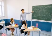 Dziś Dzień Edukacji Narodowej. Skąd się wzięło święto nauczycieli i czy uczniowie mają wolne? Nauczyciel wskazuje na tablicę podczas lekcji w klasie
